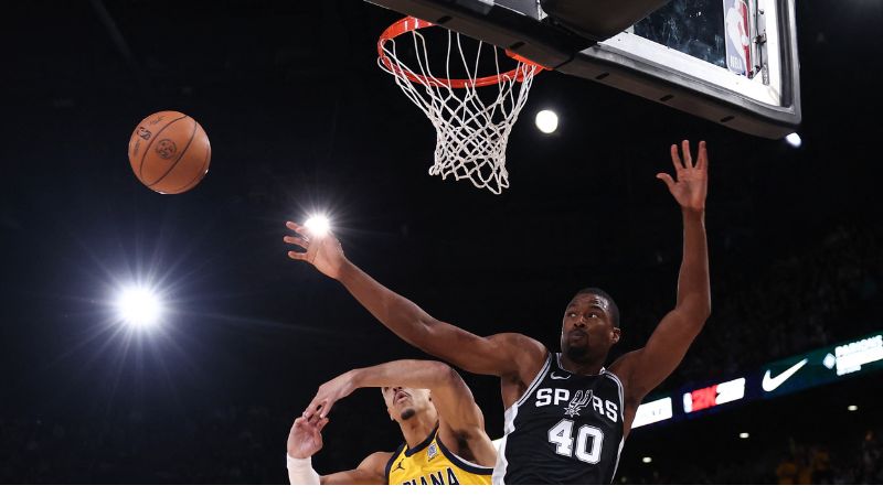 El base canadiense de los Indiana Pacers, Andrew Nembhard, y el alero estadounidense de los San Antonio Spurs, Harrison Barnes, saltan por el balón.