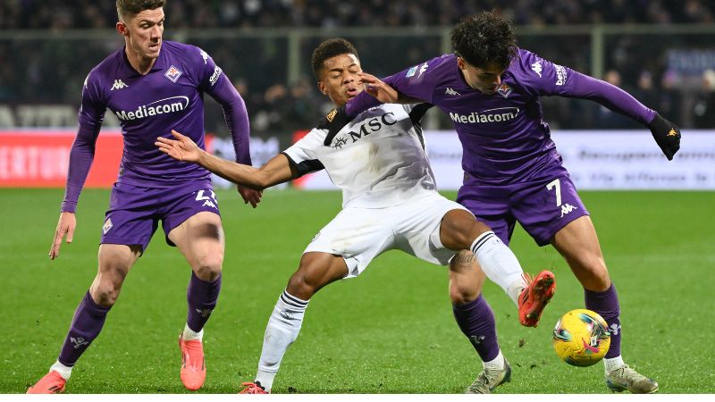 El delantero brasileño del Nápoles, David Neres, lucha por el balón con el delantero italiano de la Fiorentina, Ricardo Sottil y el defensor alemán, Robin Gosens.