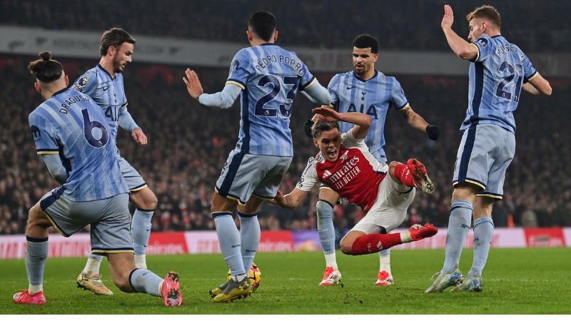 El centrocampista belga del Arsenal, Leandro Trossard , lucha por el balón con varios rivales del Tottenham Hotspur.