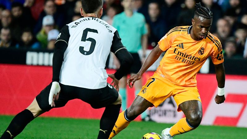 El delantero brasileño del Real Madrid, Vinicius Juniors, intenta driblar al mediocampista argentino del Valencia, Enzo Barrenechea.