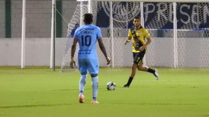 El defensa de Génssis Comaaygua, Junior García, controla el balón ante la mirada de Yeison Mejía, de Motagua.