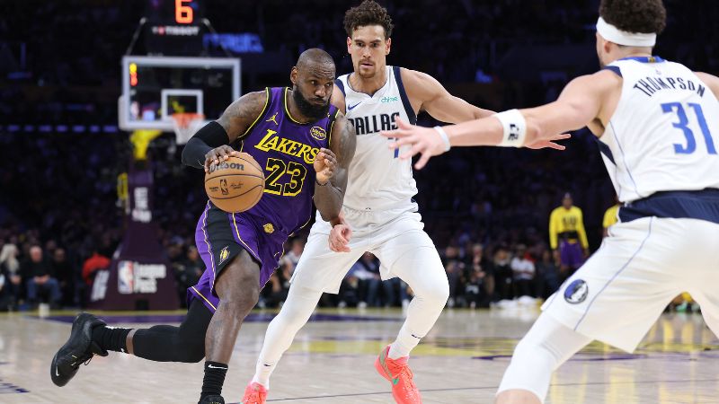 LeBron James de Los Angeles Lakers dribla hacia la defensa de Dwight Powell y Klay Thompson de los Dallas Mavericks.