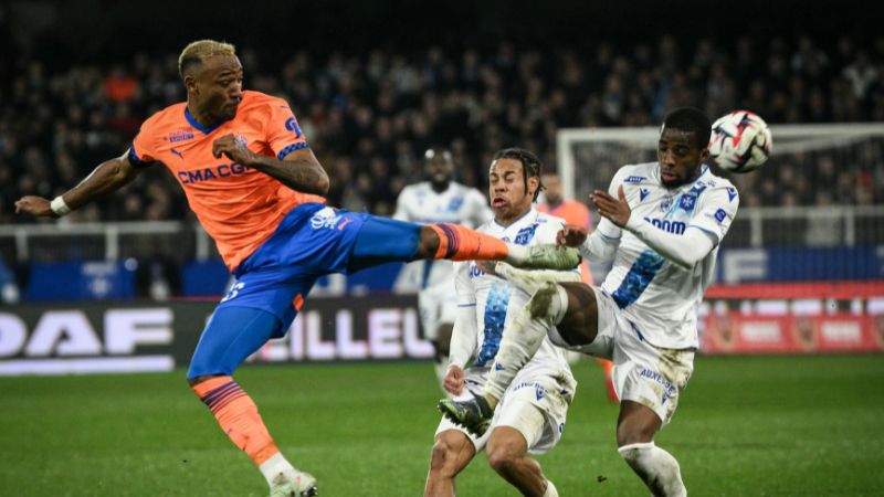 El defensa canadiense de Marsella, Derek Cornelius, lucha por el balón con el mediocampista senegalés de Auxerre, Hamed Junior Traore.