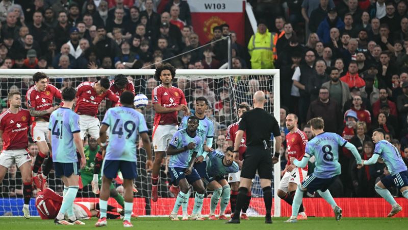 El centrocampista noruego del Arsenal, Martin Odegaard, estrella el balón en la barrera compuesta por jugadores del Manchester United.