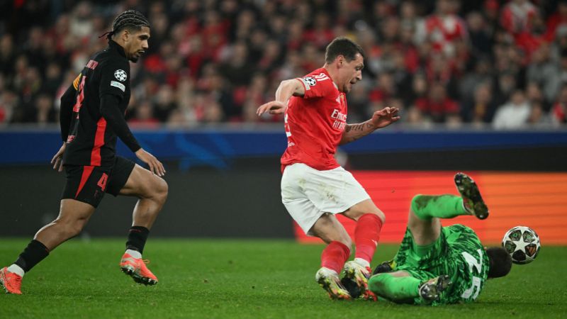 El delantero italiano del Benfica Andrea Belotti choca con el portero polaco del Barcelona Wojciech Szczesny.