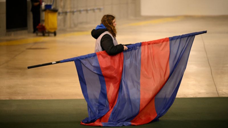 Un miembro del personal retira la bandera del FC Barcelona tras la decisión de cancelar el partido contra el Osasuna.