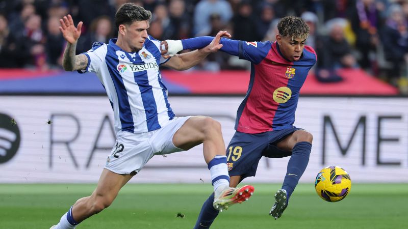 El defensa de la Real Sociedad, Javi López, y ​​Lamine Yamal, luchan por el balón.