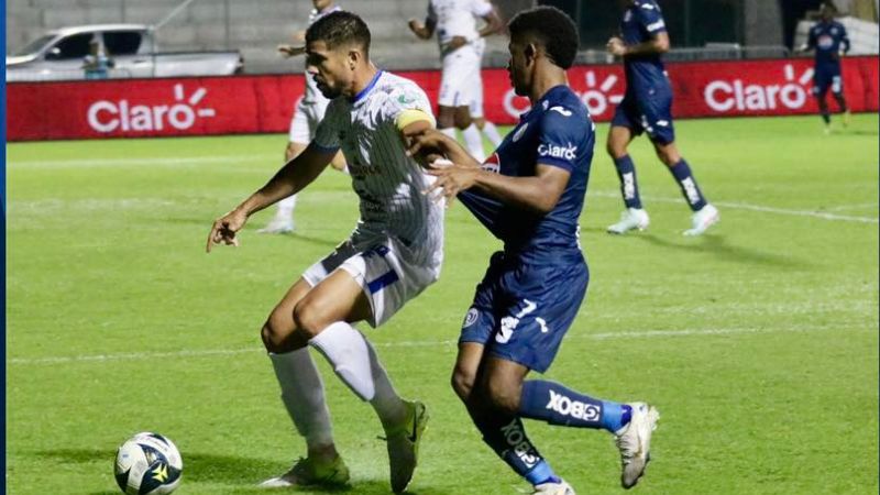 El capitán de Victoria, Marcelo Espinal, cubre el balón presionado por Jorge Serrano de Motagua.