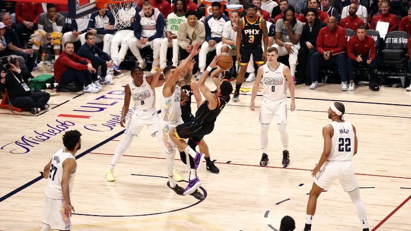 Devin Booker, de los Phoenix Suns, lanza el balón contra los Denver Nuggets.