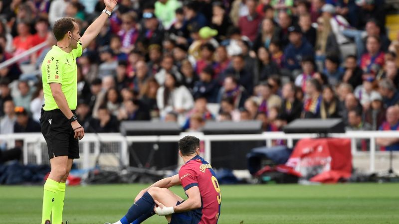 El árbitro español Melero López hace un gesto mientras el delantero polaco del Barcelona, Robert Lewandowski, se sienta en el campo después de resultar lesionado.