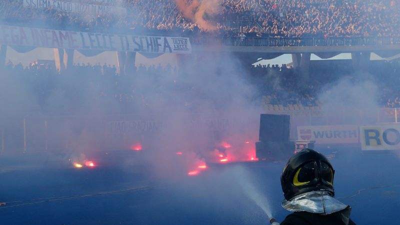 Un bombero apaga bengalas lanzadas al campo por los aficionados del Lecce.
