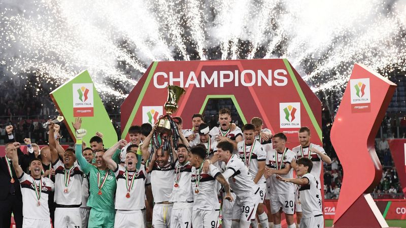 El defensa del Bolonia, Lorenzo Desilvestri, y el delantero, Riccardo Orsolini, sostienen el trofeo para celebrar la obtención de la Copa de Italia.