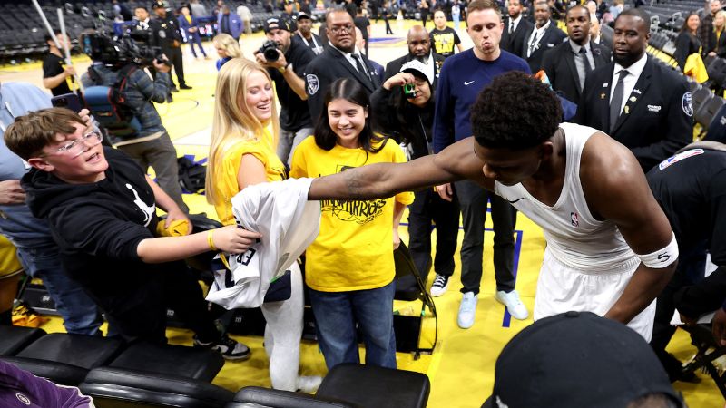 Anthony Edwards de los Minnesota Timberwolves entrega su camiseta a un joven aficionado tras derrotar a los Golden State Warriors.