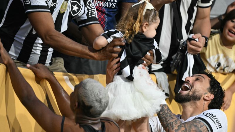 El defensa brasileño del Botafogo, Alex Telles, celebra con un bebé tras ganar el partido frente al Paris Saint-Germain de Francia.