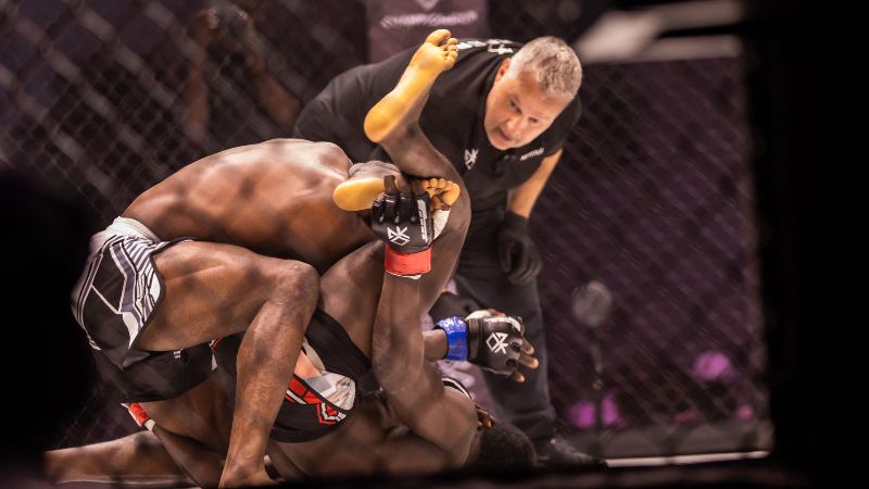 El luchador profesional nigeriano de MMA, Emmanuel Nworie, forcejea en el suelo con el beninés Jean Do Santos durante la pelea por el título de peso ligero del Campeonato Africano de Knockouts en el Centro de Conferencias Pistis de Lagos.
