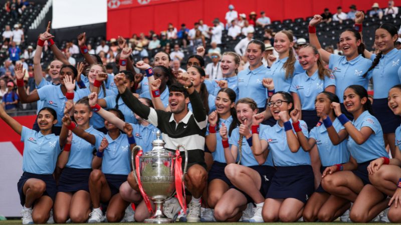 El español Carlos Alcaraz posa con recogepelotas mientras celebra con el trofeo después de ganar contra el checo Jiri Lehecka en su partido final de tenis individual masculino en el Campeonato de tenis HSBC ATP en Queen's Club.