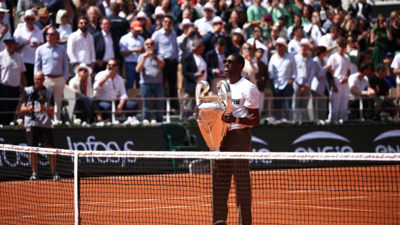 El delantero francés del Paris Saint-Germain, Ousmane Dembélé, alza el trofeo de la UEFA Champions League en la cancha Philippe-Chatrier durante el Abierto de Francia.