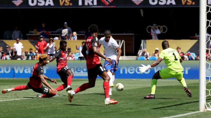 Malik Tillman de Estados Unidos anota un gol contra Marvin Phillip de Trinidad y Tobago.