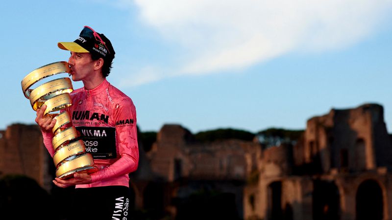 El ciclista británico Simon Yates, del equipo Visma-Lease a Bike, con la maglia rosa de líder de la clasificación general, celebra su victoria con el Trofeo Senza Fine en el podio tras la 21.ª y última etapa y su victoria en la 108.ª edición del Giro de Italia.