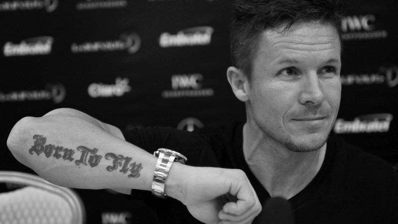 Felix Baumgartner mostrando su tatuaje con la frase "nacido para volar".