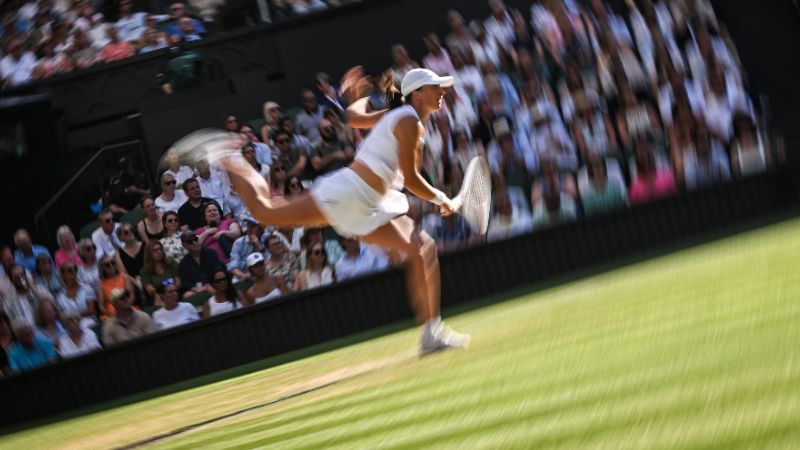 La polaca Iga Swiatek le sirve a la suiza Belinda Bencic durante su partido de semifinales de Wimbledon.