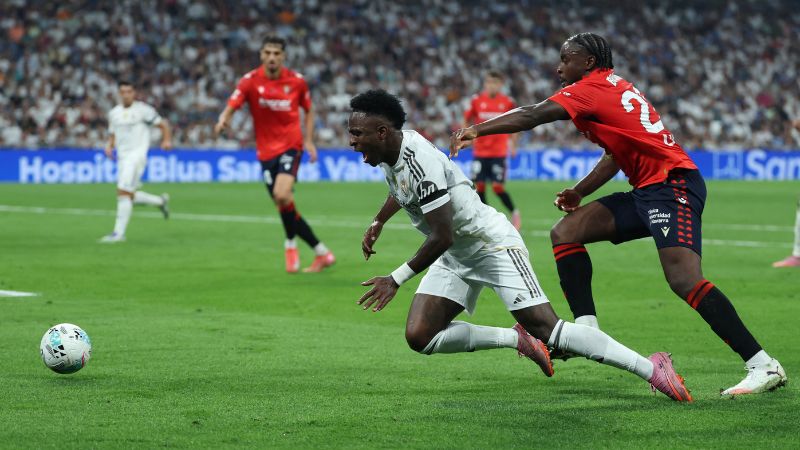 El delantero brasileño del Real Madrid Vinicius Junior y el defensa camerunés de Osasuna Flavien Boyomo disputan el balón.
