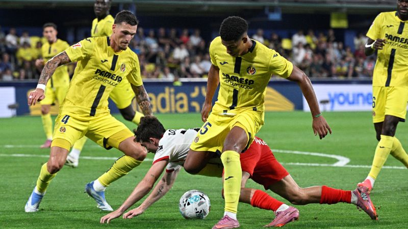 El defensa español del Girona, Joel Roca, lucha por el balón con los jugadores del Villarreal, Rafa Marín y Santiago Mourino.