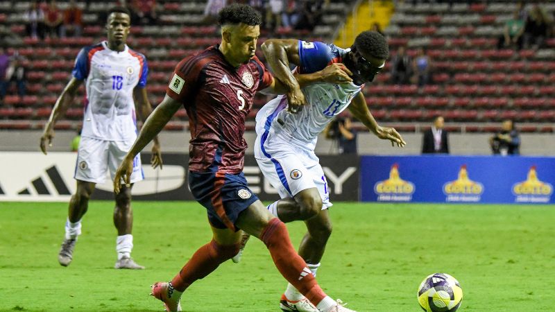 El defensa costarricense Julio Cascante y el mediocampista haitiano 0Duke Lacroix disputan el balón.