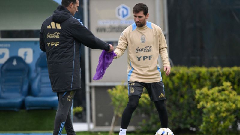 El entrenador de Argentina, Lionel Scaloni, le entrega una camiseta de entrenamiento al delantero Lionel Messi.